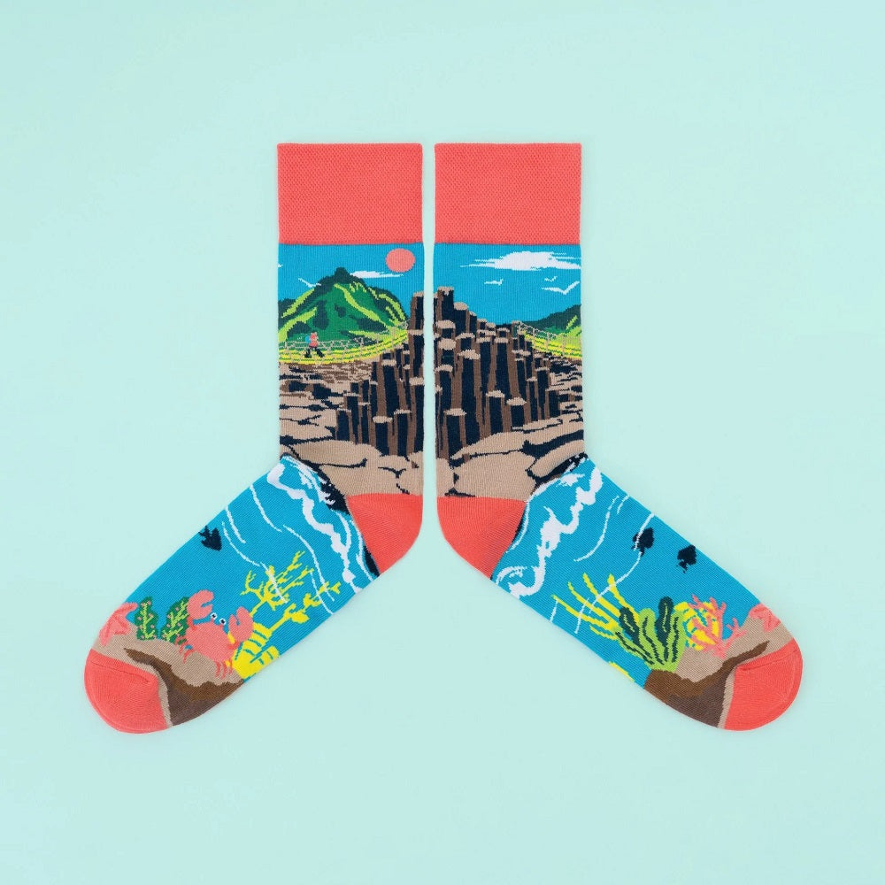 Socks with the Giants Causeway and a rope bridge behind. The foot is an underwater scene. With coral toes, heels, and band.