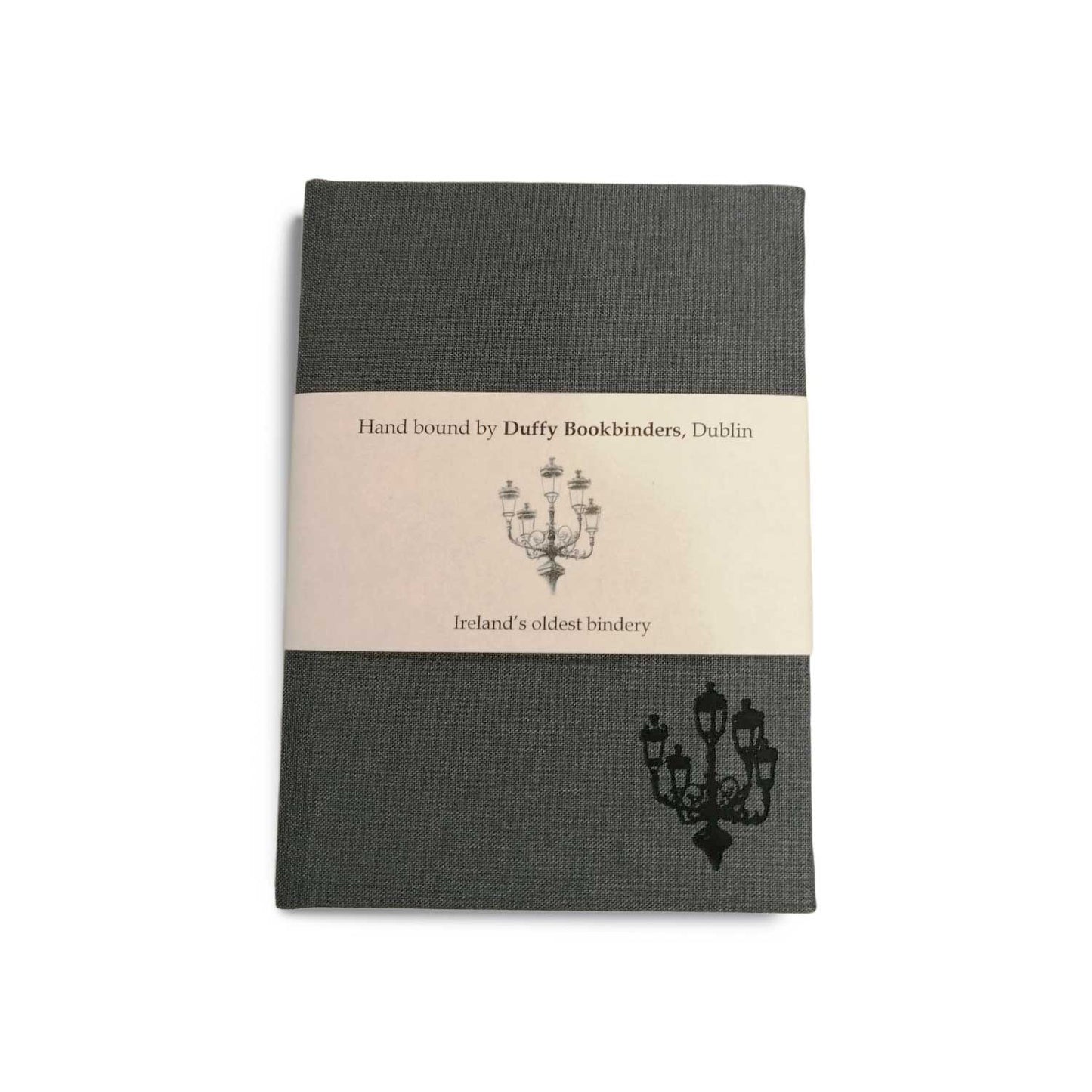 A grey clothbound notebook with a cream belly band around the centre. There is a simple line illustration of a street lamp with five lanterns in the bottom right corner of the notebook and on the band.