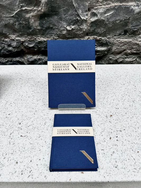 Two Blue NGI and Duffy bookbinders notebooks with a National Gallery of Ireland label on a stone surface