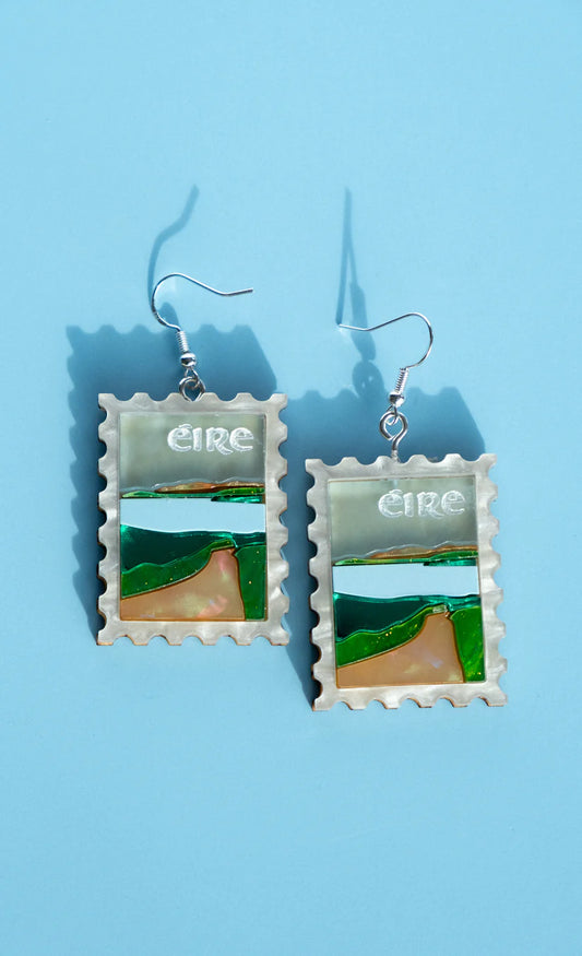 Pair of earrings with postage stamp design on a blue background