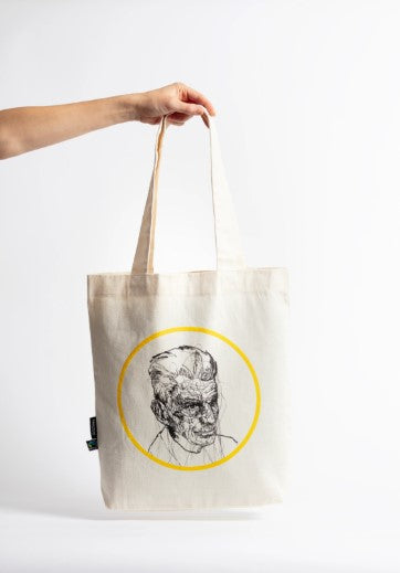 White tote bag with a sketchy style drawing of Samuel Beckett in the middle, inside a yellow circle.