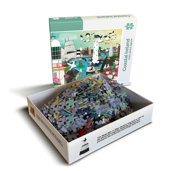 A transparent image of an open jigsaw box. The front of the box is standing up and has the image of the jigsaw which is a coastal scene featuring iconic landmarks of Ireland. The other half of the box is on its back and shows the pile of pieces.
