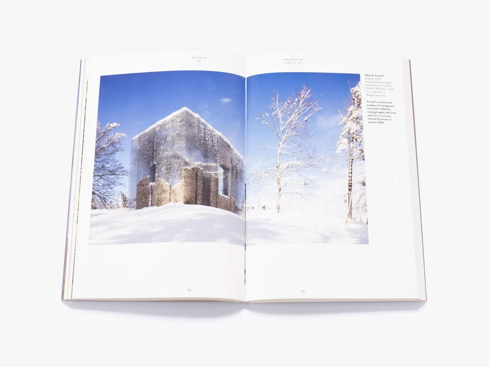 A photo of a snowy landscape with a large mesh wire cube across two pages. Inside are large square stones on different sizes.