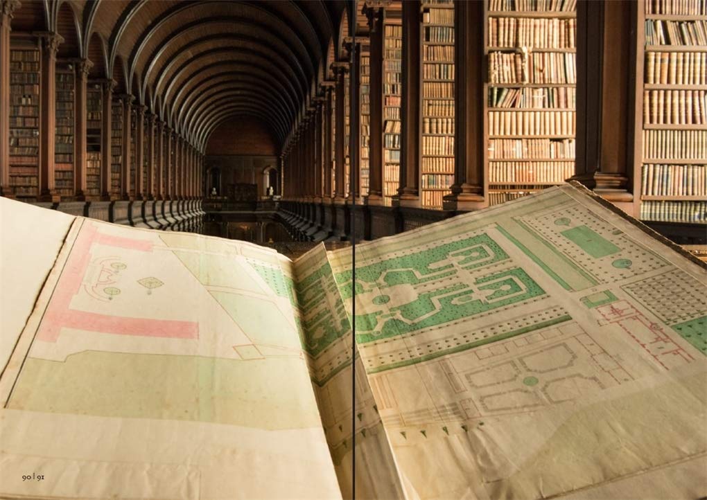 A photo of an open, old book at an angle so the viewer can see over the top to the rest of the library with the shelves of old books and arched ceiling.